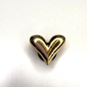 May include: A gold-colored heart-shaped charm with a glossy finish. The charm is set against a white background, highlighting its shape and metallic sheen. The heart is a classic symbol of love and affection.