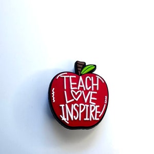 May include: Red apple charm with a white outline and the words "Teach Love Inspire" written on it.