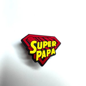 Op de afbeelding: Rood en zwart superheldenembleem met gele tekst "SUPER PAPA".