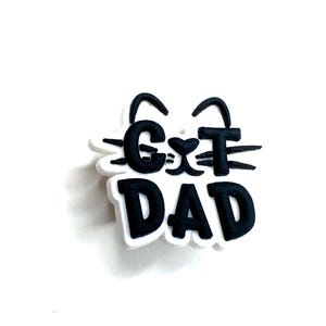 Peut inclure: Breloque noir et blanc avec un visage de chat et le texte "Cat Dad".
