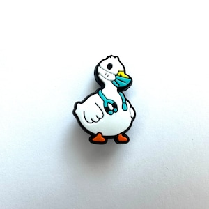 May include: A white duck wearing a blue face mask and a stethoscope. The duck has orange feet and a yellow beak.