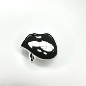 May include: Black and white illustration of a pair of lips with a tongue sticking out. The lips are dripping with black paint.