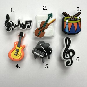 May include: Six colorful musical instrument charms, including a guitar, piano, violin, drum, and two treble clefs.