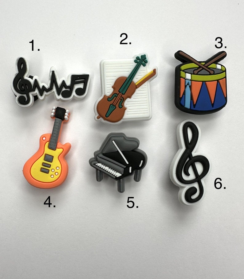 May include: Six colorful musical instrument charms, including a guitar, piano, violin, drum, and two treble clefs.