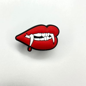 May include: Red lips with white fangs and a single drop of blood dripping from the bottom. Halloween themed charm.