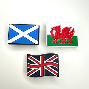 May include: Three small, colorful, plastic flags. The flags are of Scotland, Wales, and the United Kingdom. The flags are on a white background.