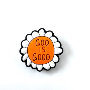 May include: Orange and white flower charm with the text "God is Good" in black lettering.
