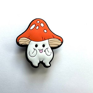 May include: A white mushroom character with a red and white mushroom cap, wearing a happy expression with its tongue sticking out. The character has small arms and legs.