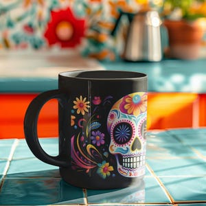 May include: A black ceramic mug featuring a colorful sugar skull graphic on the side. The skull is decorated with vibrant floral patterns in shades of pink, yellow, blue, and purple. The mug has a curved handle and a smooth, matte black finish.
