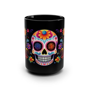 May include: Black ceramic mug with a colorful sugar skull design. The skull has bright pink, blue, yellow, and orange details. The background is black with floral accents.