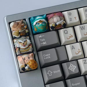 Puede incluir: Primer plano de un teclado mecánico con teclas personalizadas. Las teclas presentan diseños de personajes detallados, coloridos y caprichosos, incluyendo un ninja, un oso con un cuchillo, un lobo, un cerdo con un escudo y un dragón. El teclado tiene teclas grises y blancas.