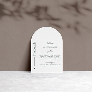 May include: White card with rounded edges and a black border. The text "The Details" is printed vertically on the left side of the card. The text "hitolo" is printed in cursive at the top of the card, followed by "The Magnolia at Willow City Park Hotel and Spa". The text "gifts" is printed in cursive, followed by "What matters to us most is having you there on our special day. However, if you do wish to buy us a gift, we have a gift list at Prezola. Please see the card enclosed for details."