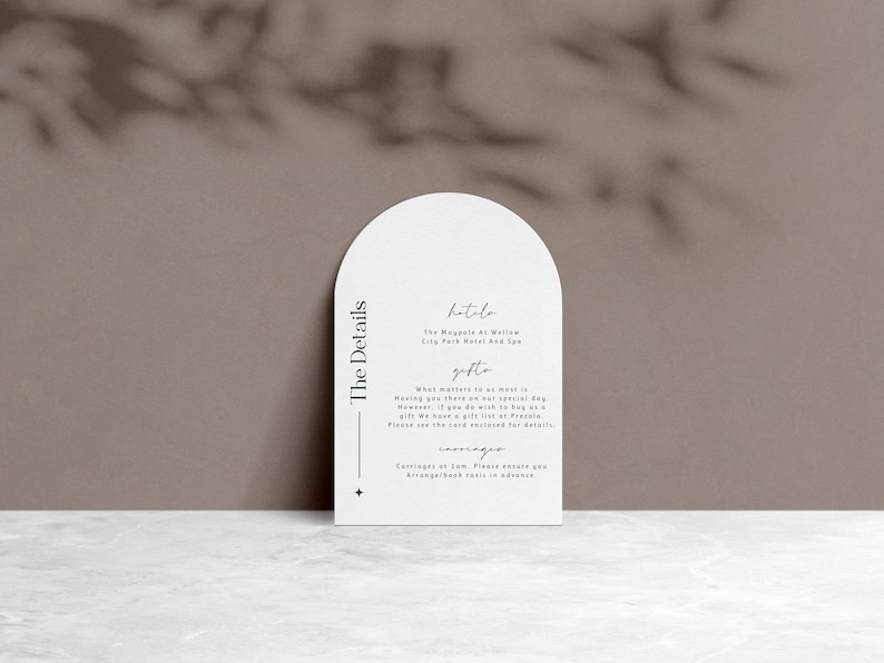 May include: White card with rounded edges and a black border. The text "The Details" is printed vertically on the left side of the card. The text "hitolo" is printed in cursive at the top of the card, followed by "The Magnolia at Willow City Park Hotel and Spa". The text "gifts" is printed in cursive, followed by "What matters to us most is having you there on our special day. However, if you do wish to buy us a gift, we have a gift list at Prezola. Please see the card enclosed for details."