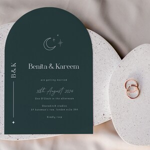 May include: A dark green wedding invitation with a crescent moon and star design. The invitation reads "Benita & Kareem are getting married 30th August 2024 One O'Clock in the afternoon Shoreditch studios 37 bateman's row, london ec2a 3hh Kindly rsvp"