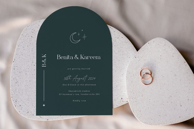 May include: A dark green wedding invitation with a crescent moon and star design. The invitation reads "Benita & Kareem are getting married 30th August 2024 One O'Clock in the afternoon Shoreditch studios 37 bateman's row, london ec2a 3hh Kindly rsvp"
