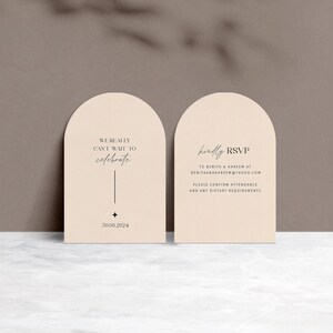 May include: Two peach-colored arched cards with rounded tops. The left card has the text "WE REALLY CANT WAIT TO celebrate" and the date "30.08.2024". The right card has the text "kindly RSVP TO BERITA & KAREEM AT BENITAANDKAREEN@YAHOO.COM PLEASE CONFIRM ATTENDANCE AND ANY DIETARY REQUIREMENTS".