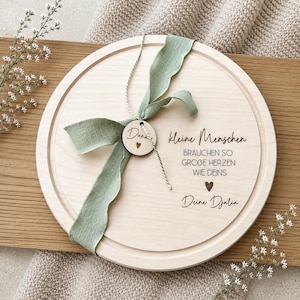 May include: A round wooden serving board with a light green ribbon and a small wooden tag that says "Danke". The board has the text "kleine Menschen brauchen so gro&szlig;e Herzen wie deins Deine Djalia" engraved on it.