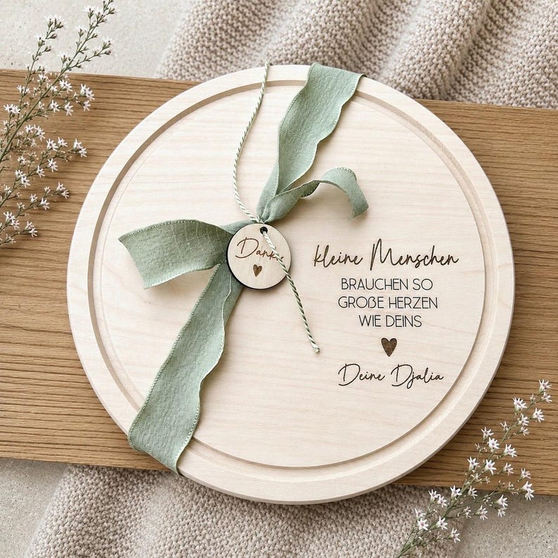 May include: A round wooden serving board with a light green ribbon and a small wooden tag that says "Danke". The board has the text "kleine Menschen brauchen so gro&szlig;e Herzen wie deins Deine Djalia" engraved on it.