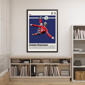 May include: A poster featuring a blue and white background with a photo of a soccer player in mid-air kicking a soccer ball. The poster has the text "F7" and "Antoine Griezmann" on it.