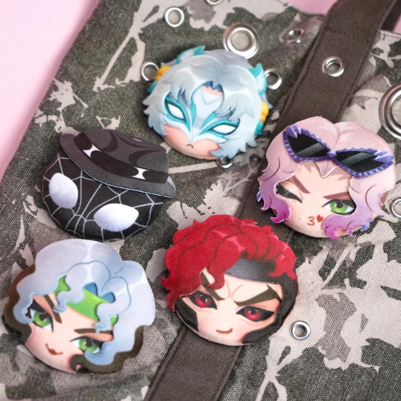 A set of five plush head pin badge buttons attached to a camouflage tote bag.