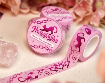 May include: Pink washi tape with a repeating pattern of a black cat, a scorpion, and a chain. The tape is 20mm wide and 10m long. The tape is packaged in a clear plastic container with a pink label that says "Hexoglyphs 20mm x 10m washi tape".