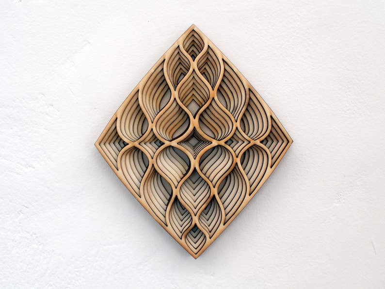 May include: A geometric wall art piece made of wood with a layered design of overlapping curves. The piece is diamond-shaped and has a light brown color.