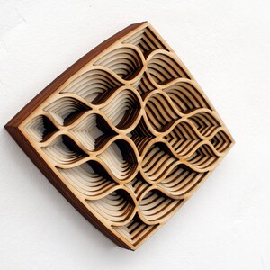 May include: A wooden wall art piece with a geometric pattern of overlapping layers. The piece is made of light and dark wood and has a square shape.