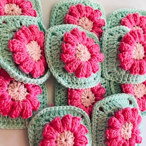 Può includere: Quadrati all'uncinetto fatti a mano con un design floreale. Ogni quadrato presenta un fiore rosa acceso con un centro rosa chiaro, su uno sfondo verde acqua chiaro. Ideali per progetti di artigianato.