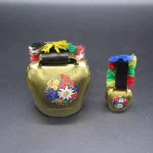 Set of 2 Vintage Brass Cow Bell. Large Cow Bell whit folwers mofif and text HALLSTATT and a small whit flowers motif.