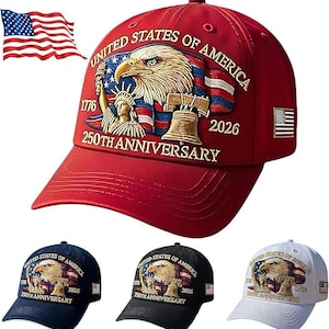 May include: A red baseball cap with an embroidered design featuring an eagle, the Statue of Liberty, and the Liberty Bell. The text reads "UNITED STATES OF AMERICA 250TH ANNIVERSARY 1776-2026". Additional caps in navy, black, and white are also shown.