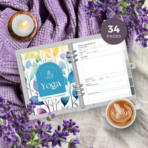 Può includere: Un diario e pianificatore di yoga grigio con una copertina dal design floreale, il testo "The Fundamental Yoga" e "Journal + Planner". Il diario è aperto a un registro di pratica quotidiana. Una tazza di caffè e una candela accesa sono anche nell'immagine.