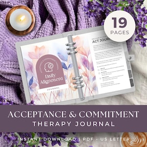 May include: A gray binder journal with the text "Daily Alignment Journal" and "Acceptance & Commitment Therapy Journal." The journal is open to a page with floral illustrations and the text "19 Pages." A lit candle and lavender sprigs are in the background.