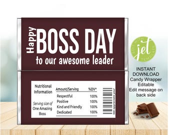 May include: A chocolate candy wrapper with the text "Happy Boss Day to our awesome leader" in white. The wrapper includes a nutritional information section with positive attributes. A small pile of chocolate pieces is visible.