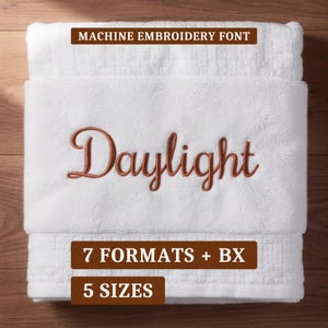 Könnte beinhalten: Ein weißes Handtuch mit dem gestickten Wort Daylight in einer kupferfarbenen Schreibschrift. Die Texteinblendungen umfassen MACHINE EMBROIDERY FONT, 7 FORMATS + BX und 5 SIZES in weißer Schrift auf braunen rechteckigen Hintergründen.