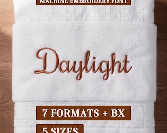 May include: A white towel featuring the embroidered word Daylight in a copper-colored script font. Text overlays include MACHINE EMBROIDERY FONT, 7 FORMATS + BX, and 5 SIZES in white lettering on brown rectangular backgrounds.