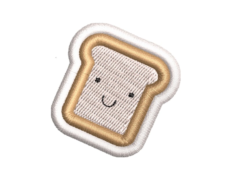 K&ouml;nnte beinhalten: Ein wei&szlig;er und brauner gestickter Aufn&auml;her in Form einer Scheibe Brot mit einem l&auml;chelnden Gesicht.