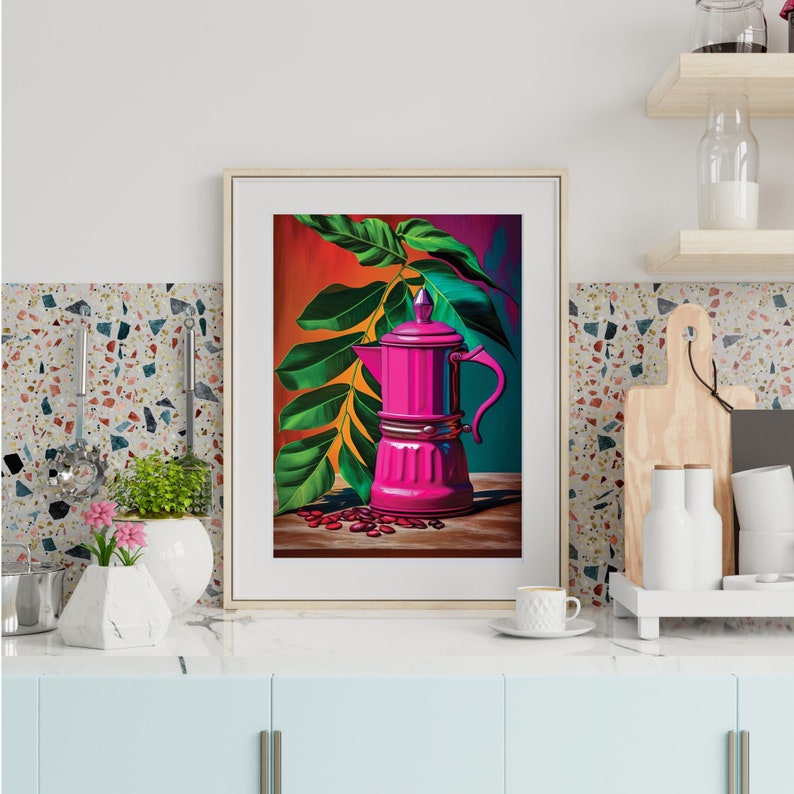 May include: Framed art print featuring a vibrant pink coffee maker with a handle, set against a backdrop of green leaves and coffee beans. The artwork has a colorful, stylized design, with a wooden table and a red, orange, and teal background.