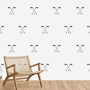 May include: White wallpaper with a repeating pattern of black crossed golf clubs. A wooden chair sits in front of the wall.
