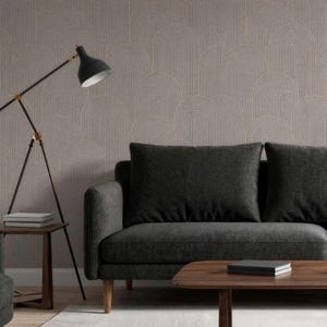 May include: A living room scene featuring a dark gray sofa with two large square cushions. A wooden coffee table and side table are in front of the sofa. The wall is decorated with a beige wallpaper with a repeating arched pattern. A black floor lamp is positioned to the left.