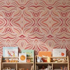May include: A room with a patterned wallpaper in shades of red and pink. Wooden bookshelves hold children's books and toys. The wallpaper design features a repeating abstract floral pattern.
