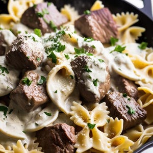 May include: A close-up of a skillet filled with creamy pasta, beef, and fresh parsley. The pasta is bowtie shaped and the beef is in bite-sized pieces.