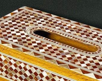May include: A wooden tissue box cover with a checkered pattern made of mother of pearl and brown wood. The cover has a rectangular opening for tissues.