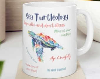 May include: White ceramic mug with a colorful sea turtle illustration and the text "Sea Turtleology" with a list of turtle-related sayings: "Keep calm and don't stress", "Move at your own pace", "Go with the flow", "Come out of your shell!" , "Age gracefully", and "Be well traveled".
