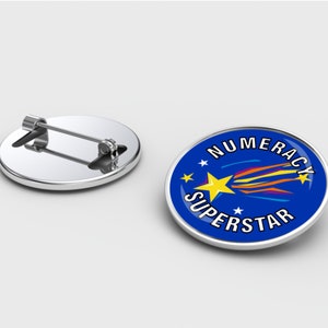 Könnte beinhalten: Eine blaue und silberne Anstecknadel mit einem gelben Stern und einem Sternschnuppen mit einem Regenbogen-Schwanz. Der Text "NUMERACY SUPERSTAR" ist in einem Kreis um den Stern geschrieben.
