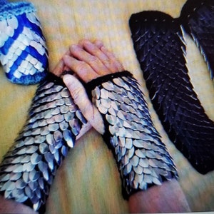 May include: Two silver chainmail gauntlets with black trim, and two black chainmail gauntlets. The gauntlets are made of small, overlapping metal scales.