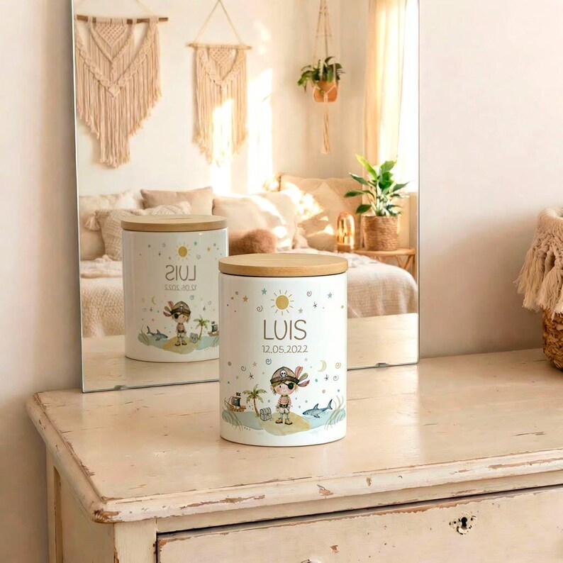 May include: White ceramic container with a wooden lid. The container features a cartoon pirate design with the name "LUIS" and the date "12.05.2022". The design includes a pirate, palm trees, a shark, and a sun.