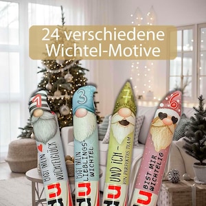 May include: Four decorative gnome figures with different designs and colors. Each gnome has a long white beard and a pointed hat. The text "24 verschiedene Wichtel-Motive" is displayed above the gnomes.