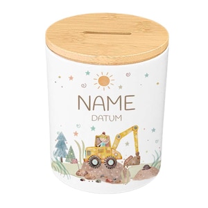 May include: White ceramic money bank with a wooden lid. The bank features a colorful illustration of a yellow excavator, trees, and the text "NAME DATUM". The design includes stars, a sun, and swirls.
