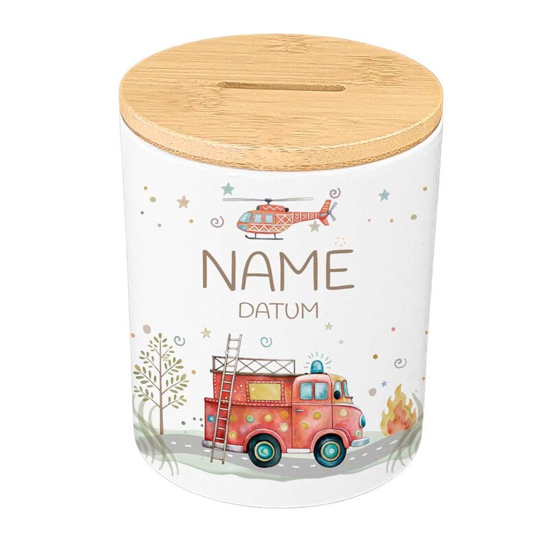 May include: White ceramic money bank with a wooden lid. The bank features illustrations of a red fire truck, a helicopter, and the words "NAME" and "DATUM". The design includes stars, a tree, and flames.