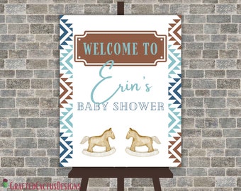 May include: Welcome to Erin's Baby Shower sign with a brown and blue geometric pattern border. The sign features two rocking horses and the text "Welcome to Erin's Baby Shower".